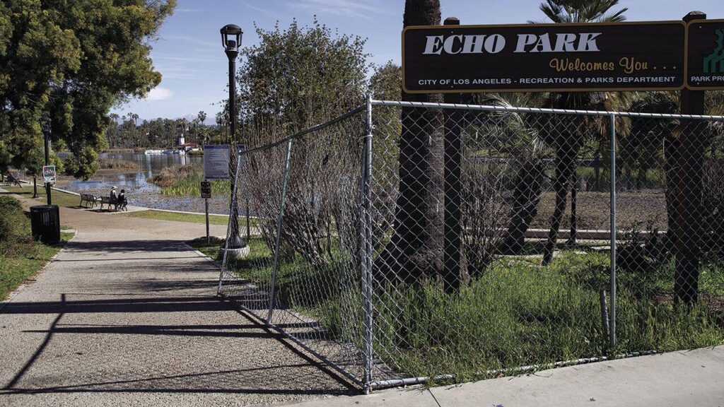 The fence surrounding Echo Park Lake is seen as a symbol for both public safety and social division. - Photo by Chris Mortenson
