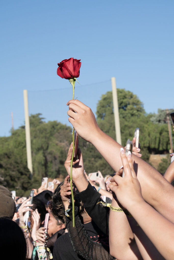 An XG fan holds up a rose from behind the barrier.
